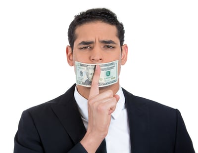 Closeup portrait of handsome corrupt guy in black suit with twenty dollar bill taped to mouth and showing shhh sign, isolated on white background. Bribery concept in politics, business, and diplomacy.