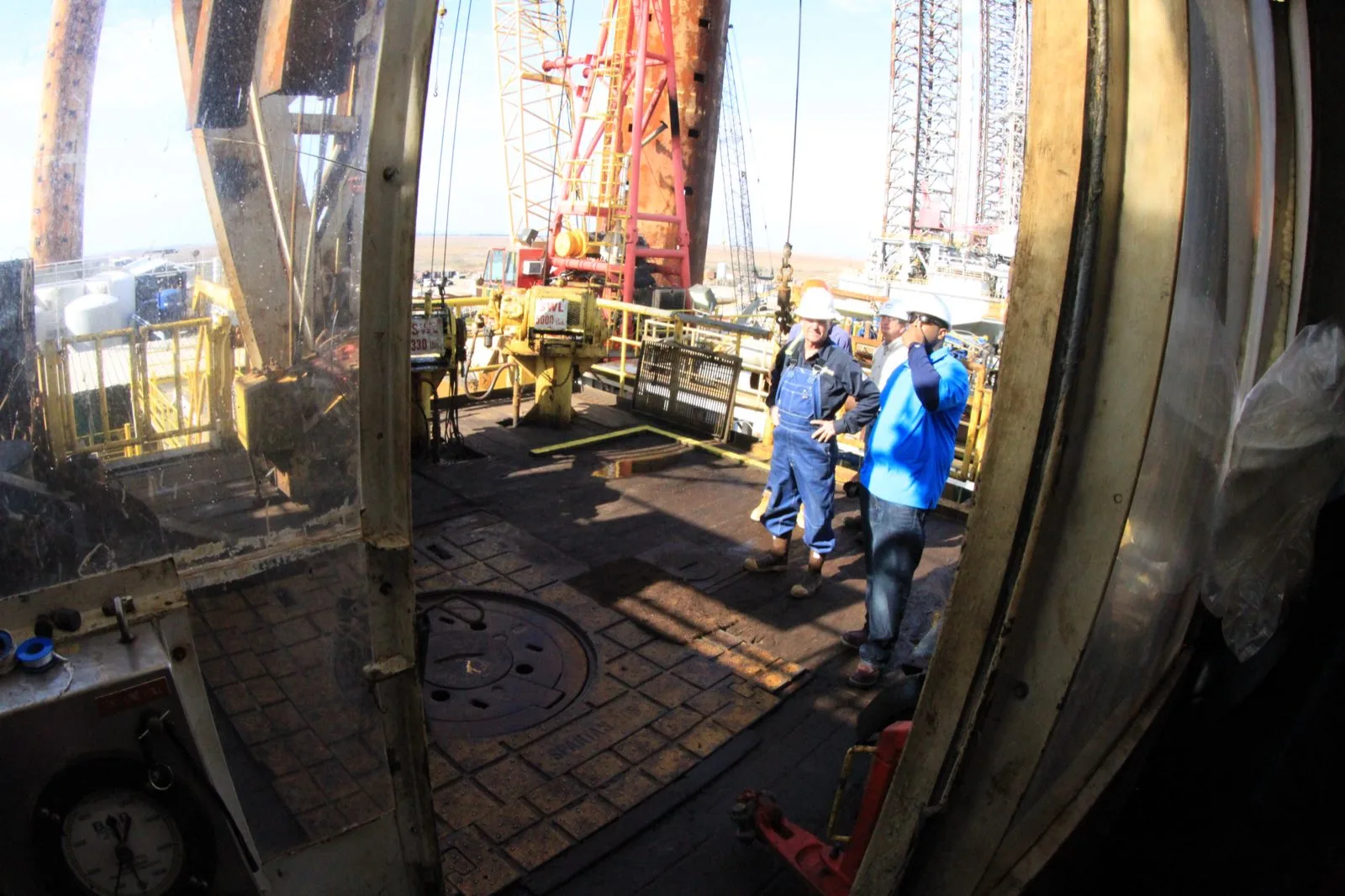 Offshore crew in coveralls and hard hats working on a drill floor