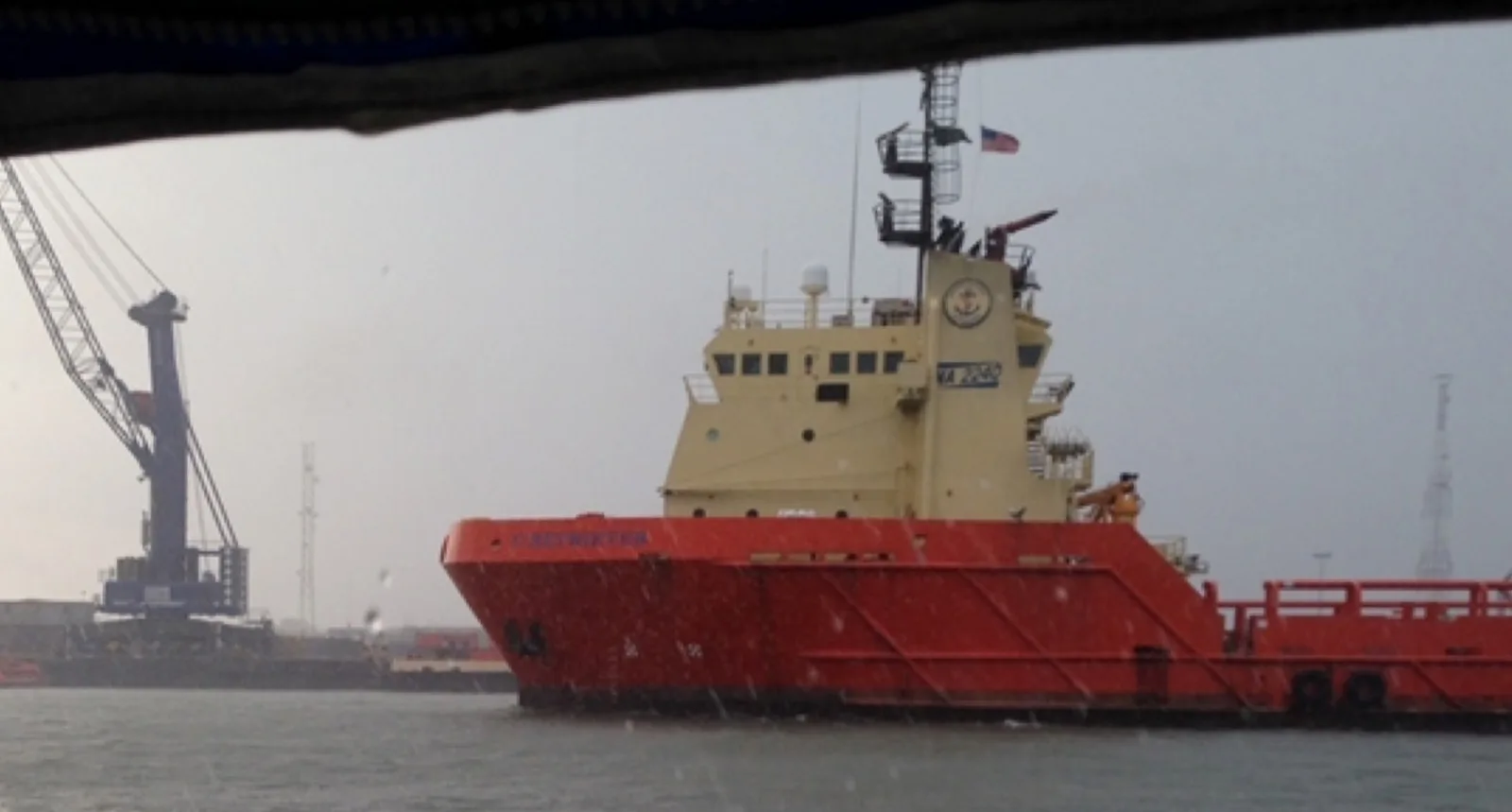 A cargo vessel moored at a port terminal beside a gantry crane