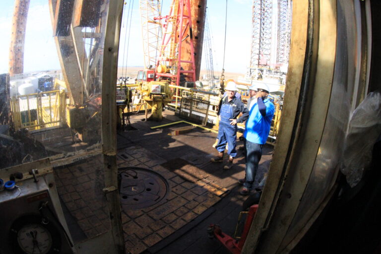 People in hard hats inspecting the drill floor of an offshore rig