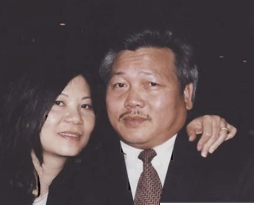 A man in a suit and tie with a woman standing beside him.