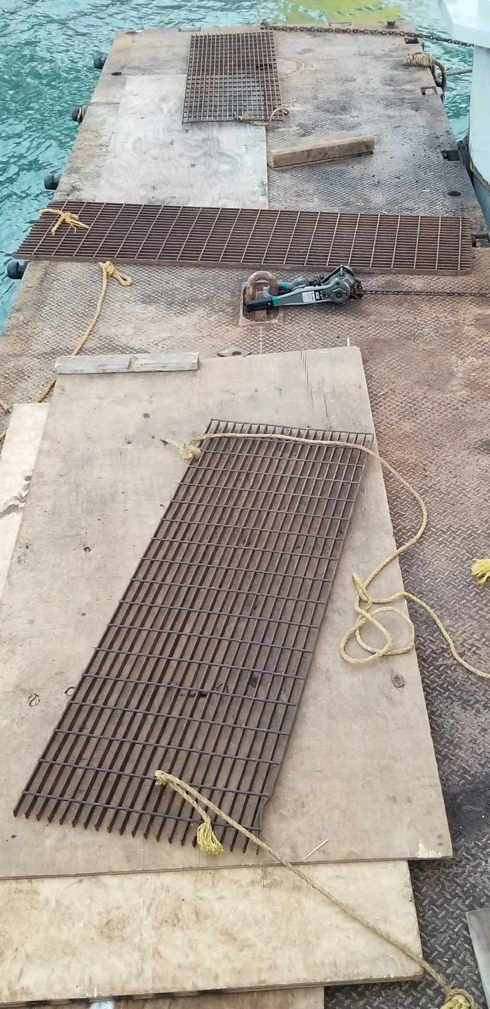 Metal grating panels and rigging equipment on a floating work deck.