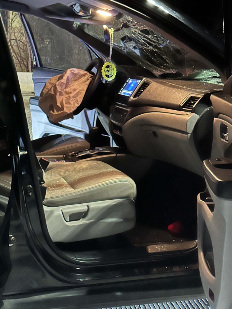 Shattered windshield and a deployed driver airbag inside an empty vehicle.