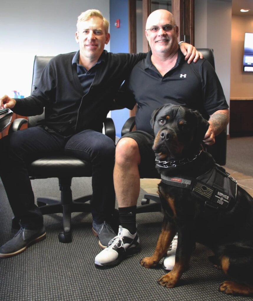 Brian Beckcom seated beside Captain Wren Thomas, with Beaux in front of them.