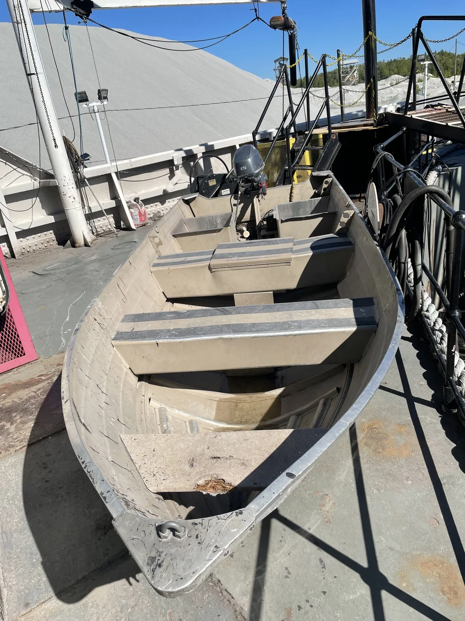 A small workboat stored on deck with bench seats and an outboard motor.