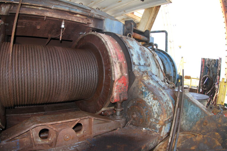 Wire rope wound around a large drilling-rig drum beside its metal housing.
