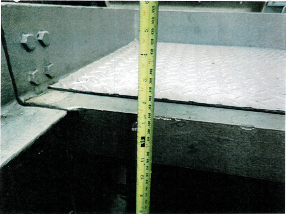 Measuring tape held vertically through a deck access opening.