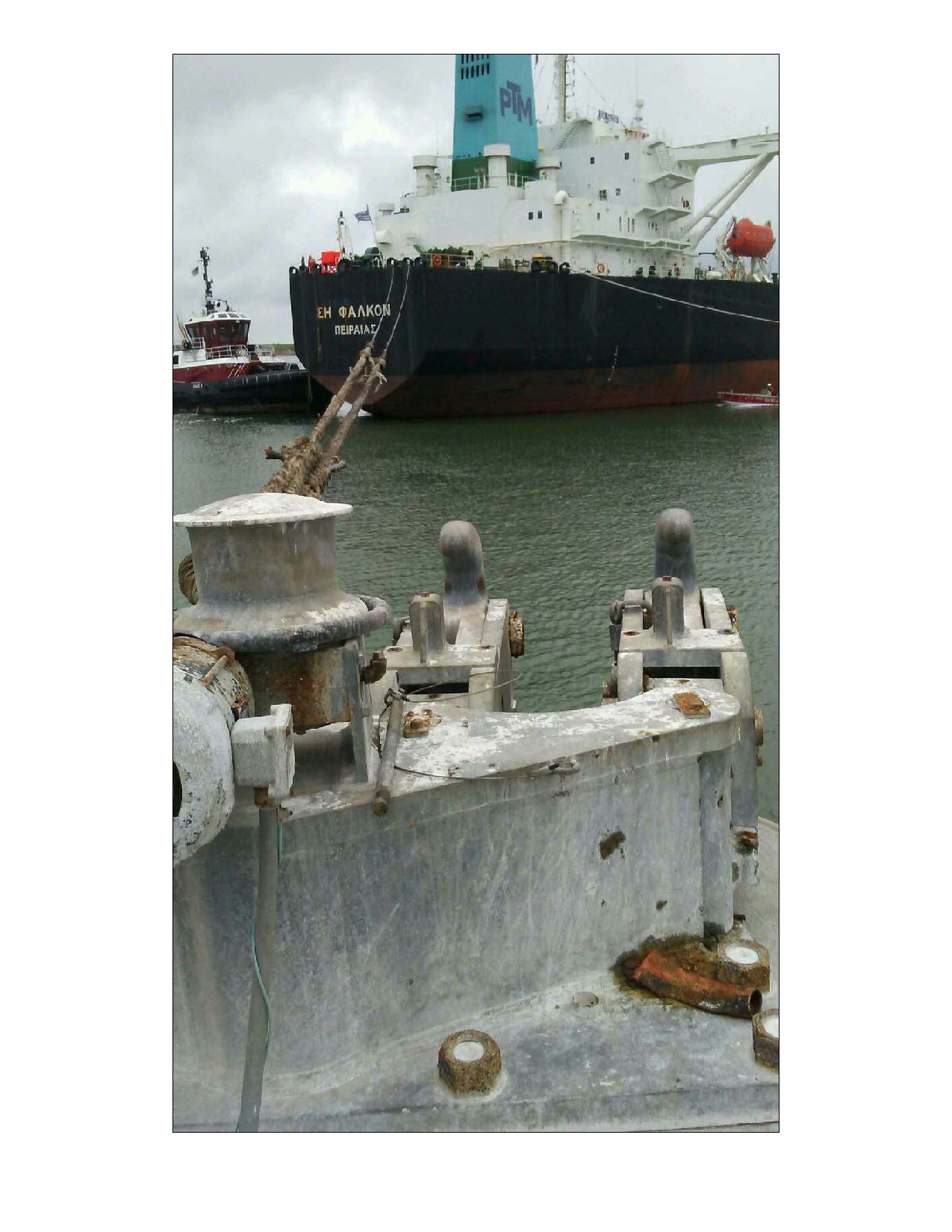 Two mooring hooks in the foreground with mooring lines and a secured ship behind them.