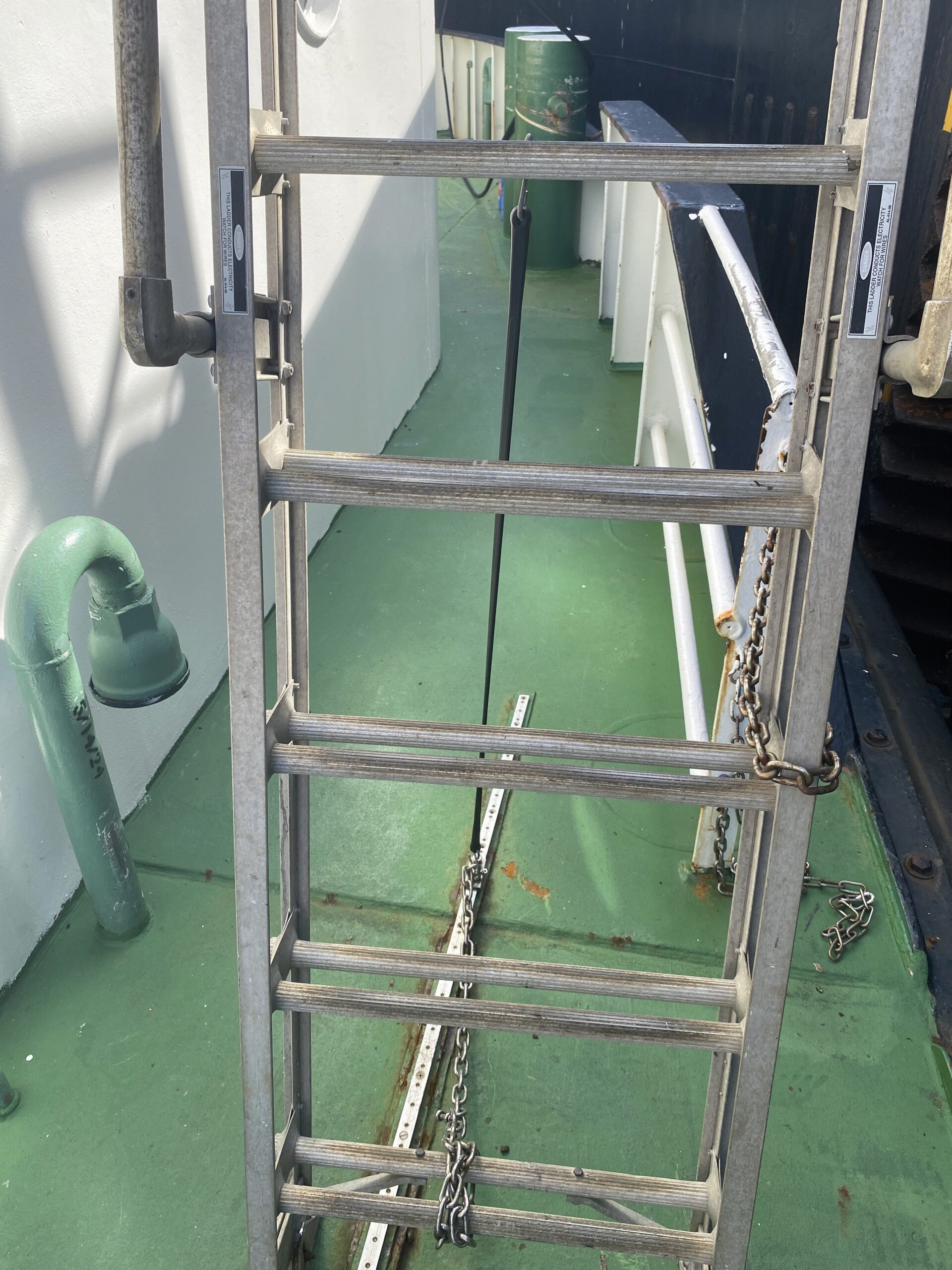 Vessel access ladder with securing chains and a track running along the green deck