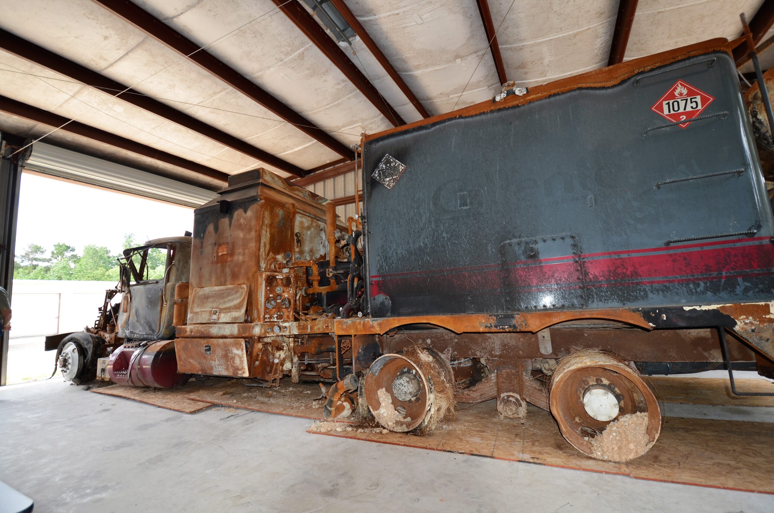 Fire-damaged hot-oiler truck inside a storage building during a later inspection.