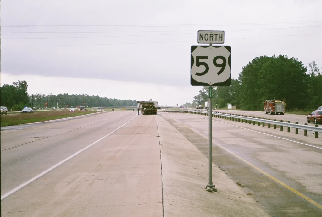U.S. 59 North sign beside the highway, with emergency vehicles farther along the roadway.